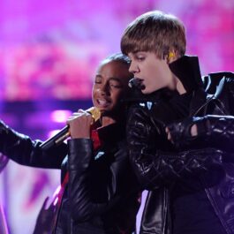 Justin Bieber și Jaden Smith îmbrăcați în ținute negre strălucitoare în timp ce cântă împreună la microfon