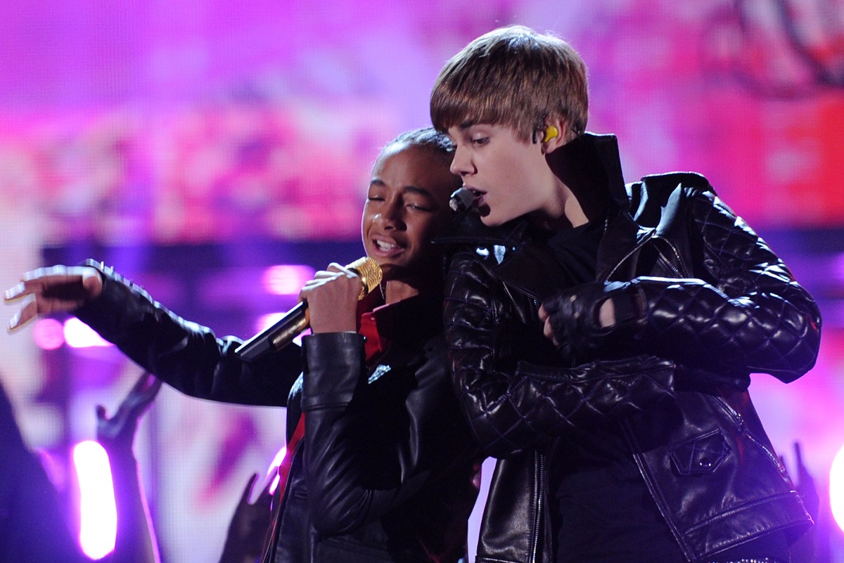Justin Bieber și Jaden Smith îmbrăcați în ținute negre strălucitoare în timp ce cântă împreună la microfon