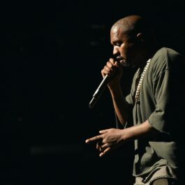 Kanye West îmbrăcată într-o ținută kaki în timp ce cântă la microfon