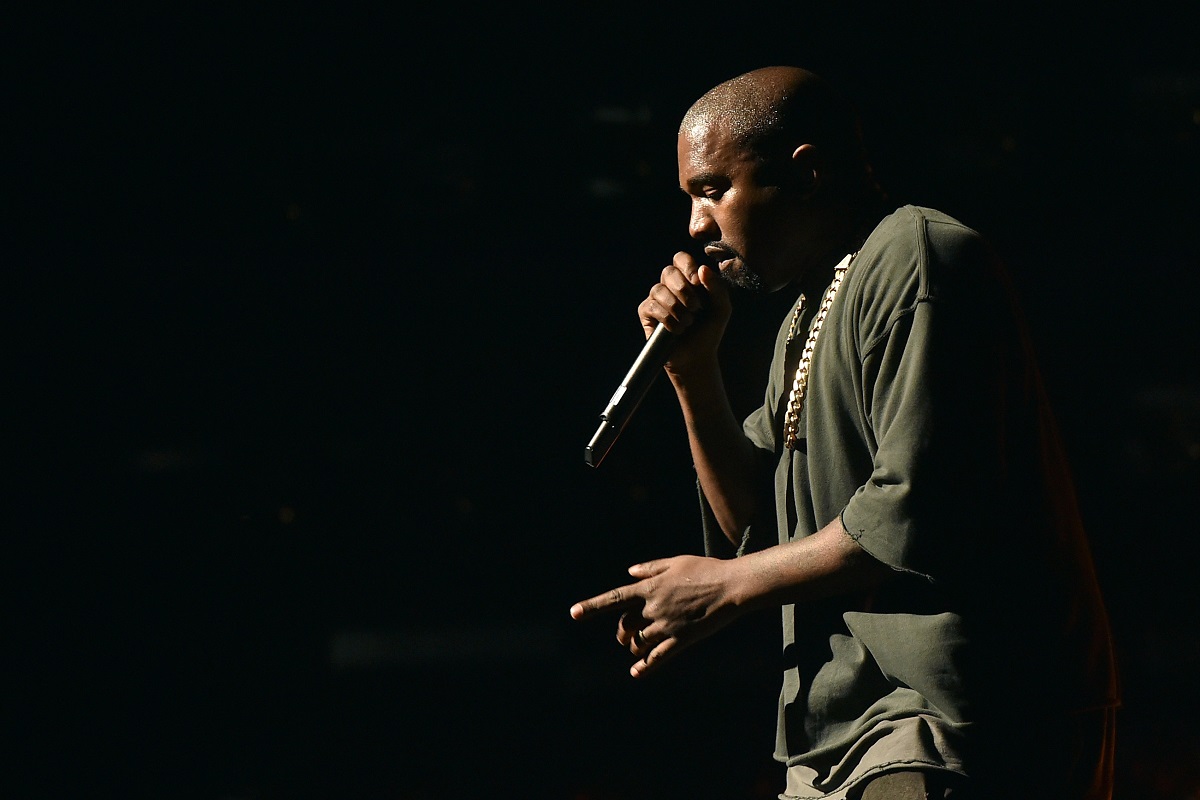 Kanye West îmbrăcată într-o ținută kaki în timp ce cântă la microfon