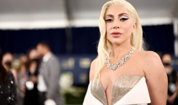 Lady Gaga îmbrăcată într-o rochie albă care are cupe aurii strălucitoare