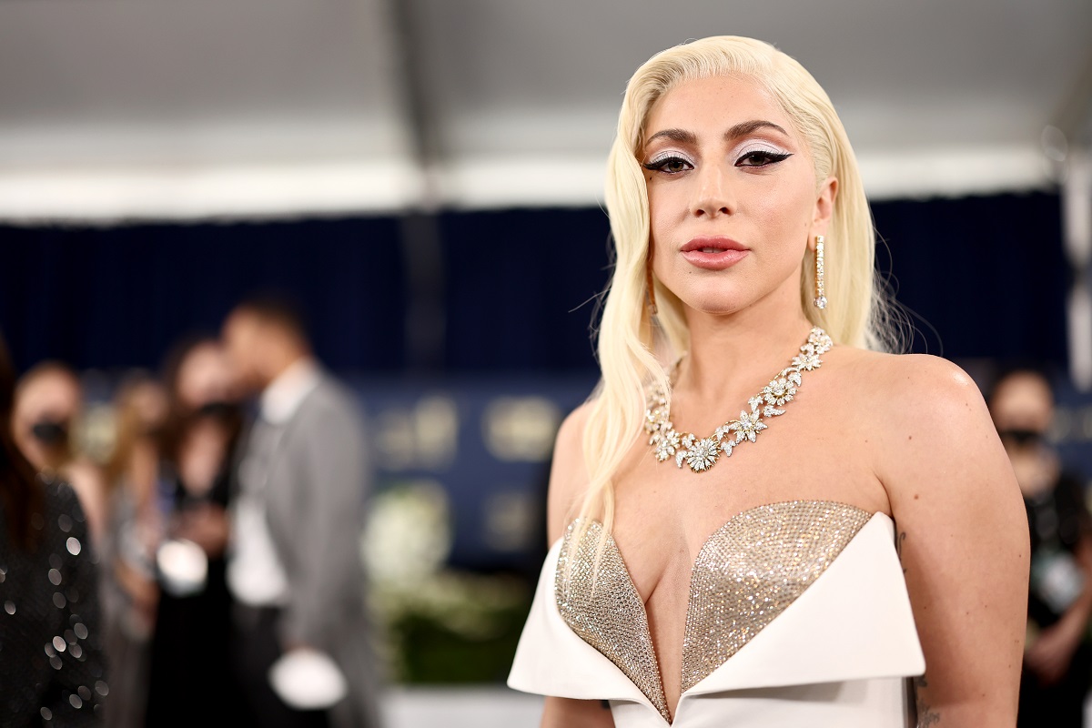 Lady Gaga îmbrăcată într-o rochie albă care are cupe aurii strălucitoare