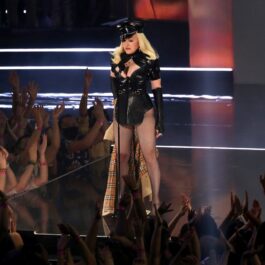 Madonna îmbrăcată într-o ținută sexy neagră de polițist în timp ce cântă pe scenă