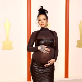 Rihanna îmbrăcată într-o ținută neagră cu detalii transparente în timp ce își mângâie burtica de gravidă