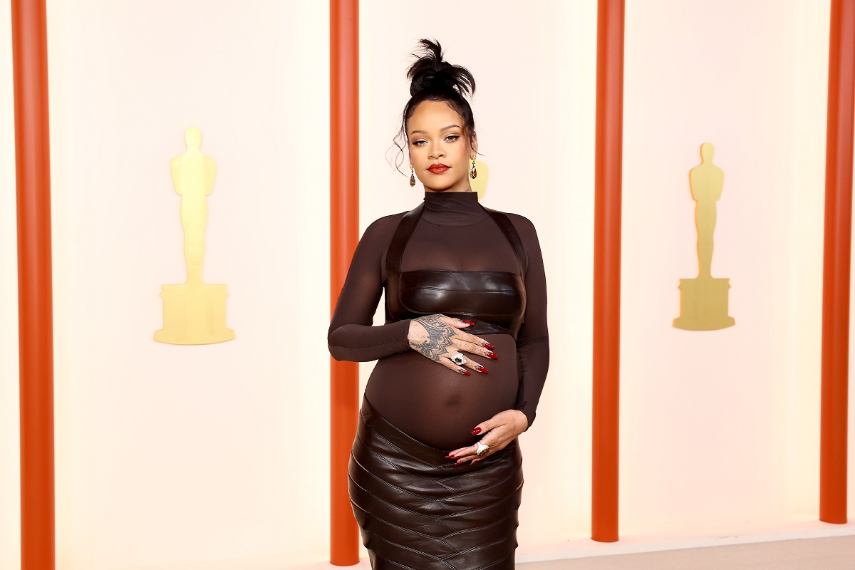 Rihanna îmbrăcată într-o ținută neagră cu detalii transparente în timp ce își mângâie burtica de gravidă