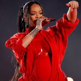 Rihanna îmbrăcată într-o ținută complet roșie în timp ce cântă la microfon și gesticulează
