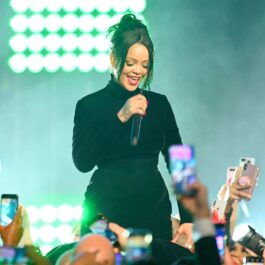Rihanna îmbrăcată într-o ținută complet neagră, cântând la microfon în timp ce este filmată de fani