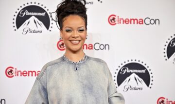 Rihanna îmbrăcată într-o bluză gri în timp ce zâmbește larg
