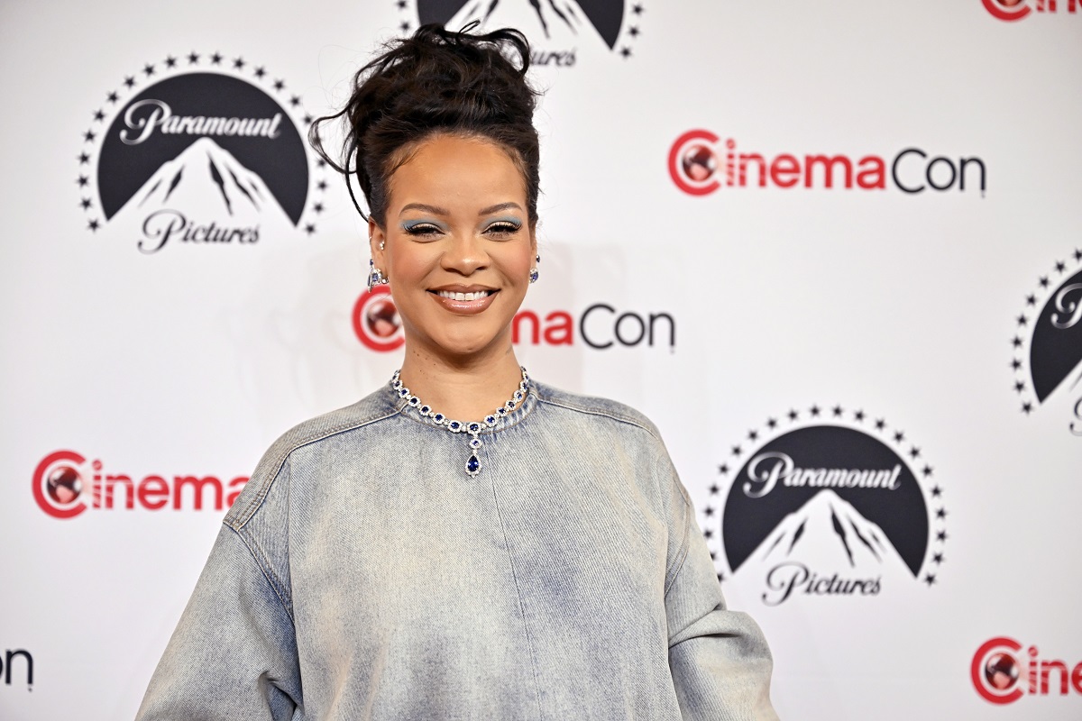 Rihanna îmbrăcată într-o bluză gri în timp ce zâmbește larg