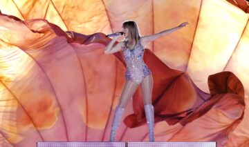 Taylor Swift îmbrăcată într-un body strălucitor și cizme asortate în timp ce cântă pe scenă
