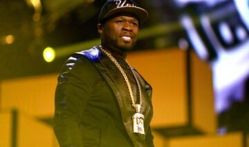 50 Cent îmbrăcat într-o ținută neagră asortată cu un lanț strălucitor