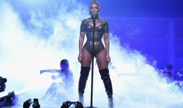 Beyonce îmbrăcată într-un body sexy de culoare gri în timp ce cântă la microfon