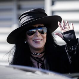 Cher îmbrăcată într-o geacă neagră asortată cu o pălărie și ochelari de soare