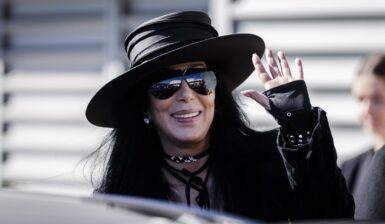 Cher îmbrăcată într-o geacă neagră asortată cu o pălărie și ochelari de soare