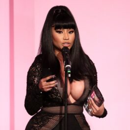 Nicki Minaj îmbrăcată într-o rochie neagră în timp ce cântă la microfon