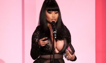 Nicki Minaj îmbrăcată într-o rochie neagră în timp ce cântă la microfon